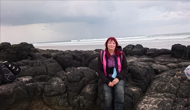 Sharon smiles at the camera while sitting on black rocks at castlerock