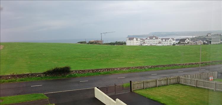 Looking from the window we see the sea behind large grassy areas and some houses