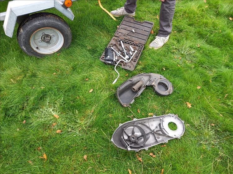 The tools and the drive belt covers spread out on the grass of the field