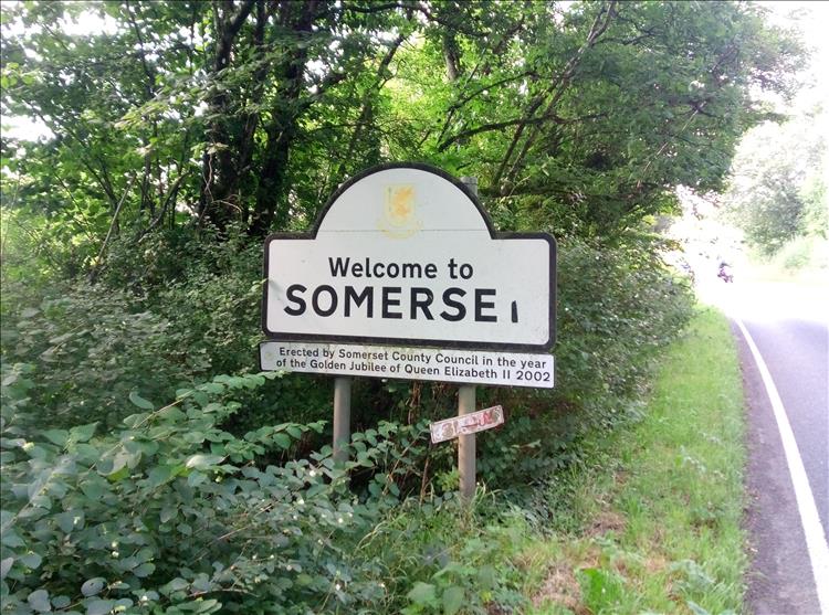A roadsign among trees welcoming drivers and riders to Somerset