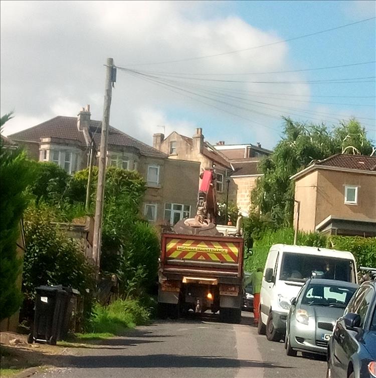 A works lorry and parked cars block the road as work continues in Bath