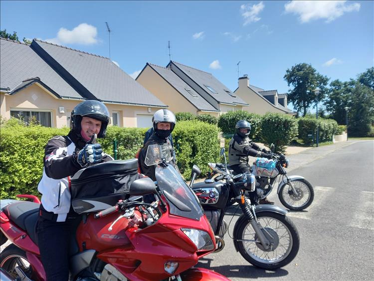 The riders on various motorcycles outside a row of modern French bungalows