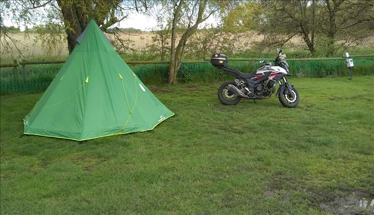 The CB500X and tipi tent at the Parkdean site, next to a tree and some mud