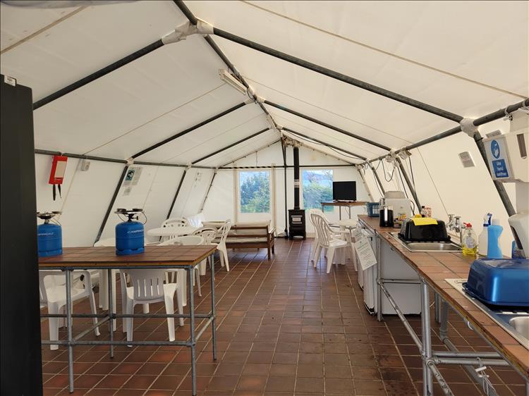 A medium sized heavy marquee with tables, chairs, camping gas stoves and sinks