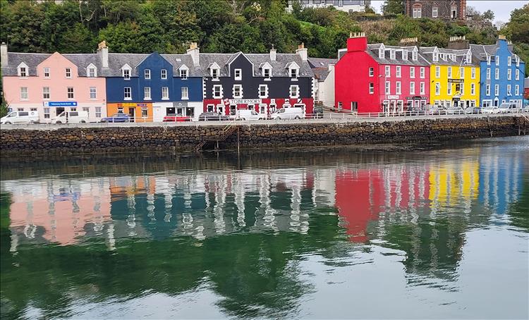 The brightly painted houses by the shore, reflected in the waters of the harbour at Tobermory