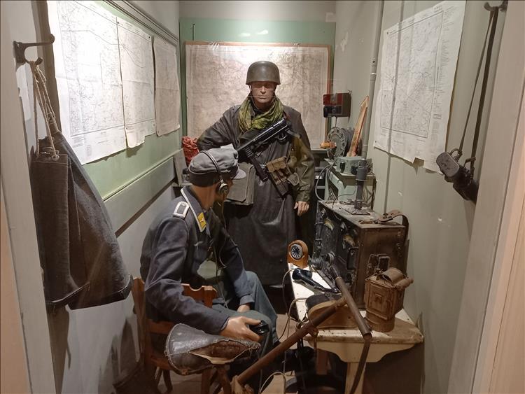 A small room with maps and radios and a couple of mannequins dressed in WW2 German unform