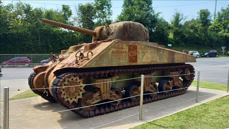 A rusty Sherman tank on a plinth outside the exhibition