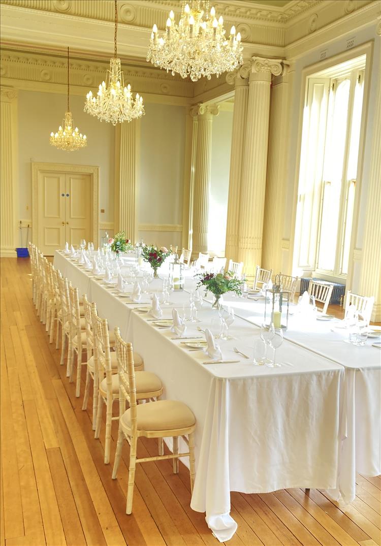Polished floors, neatly laid table in white and cream, large cream room and chandeliers, very posh