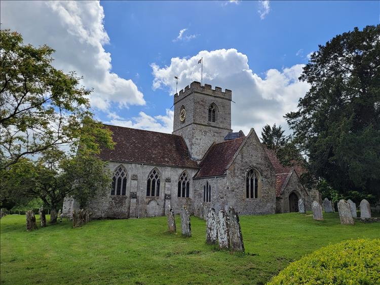An old small church and graveyard in the sunshine and trees at Dinton