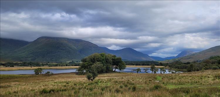 A loch and mountains, their tops covered in heavy skies seen from near The Castle