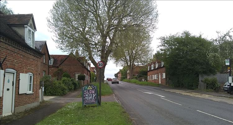 A pleasant village featuring a blackboard asking people to slow down for children