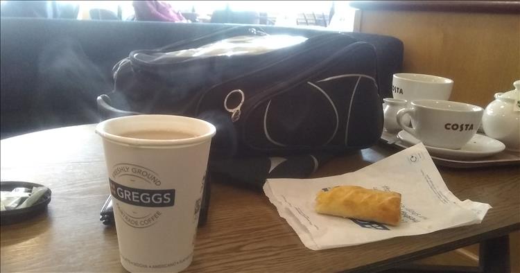 A tea in a paper cup and half eaten sausage roll from Greggs bakery at Blyth Services