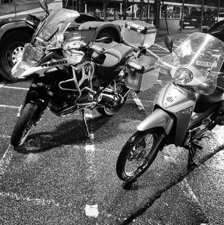 The small Innova parked next to a massive BMW GS R1200