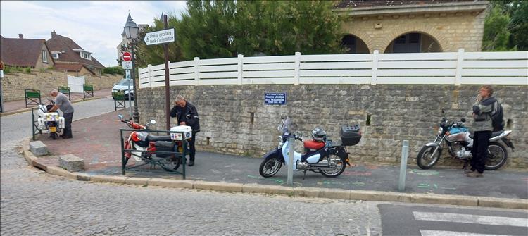 3 Honda Cubs and a CG125 parking on the footpath in Arromanche