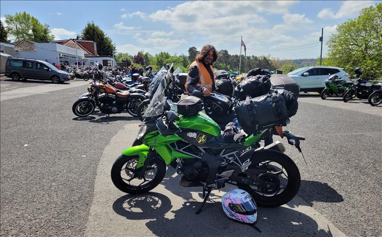 Lots of motorcycles on a car park outside the cafe in the sunshine