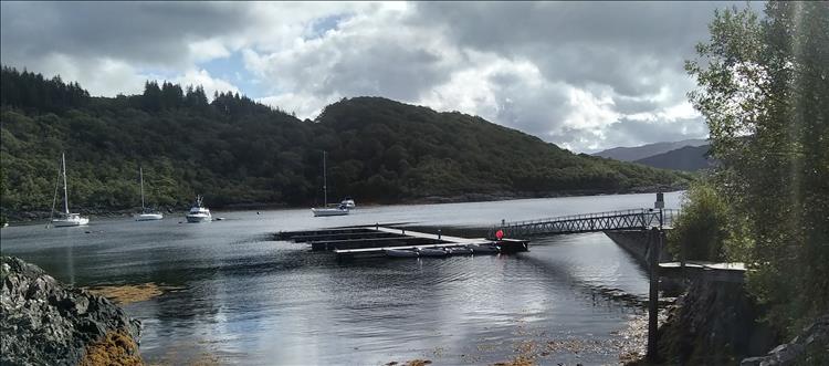 The sea loch, hills covered in trees, boats in the sheltered bay and a Jetty at Salen