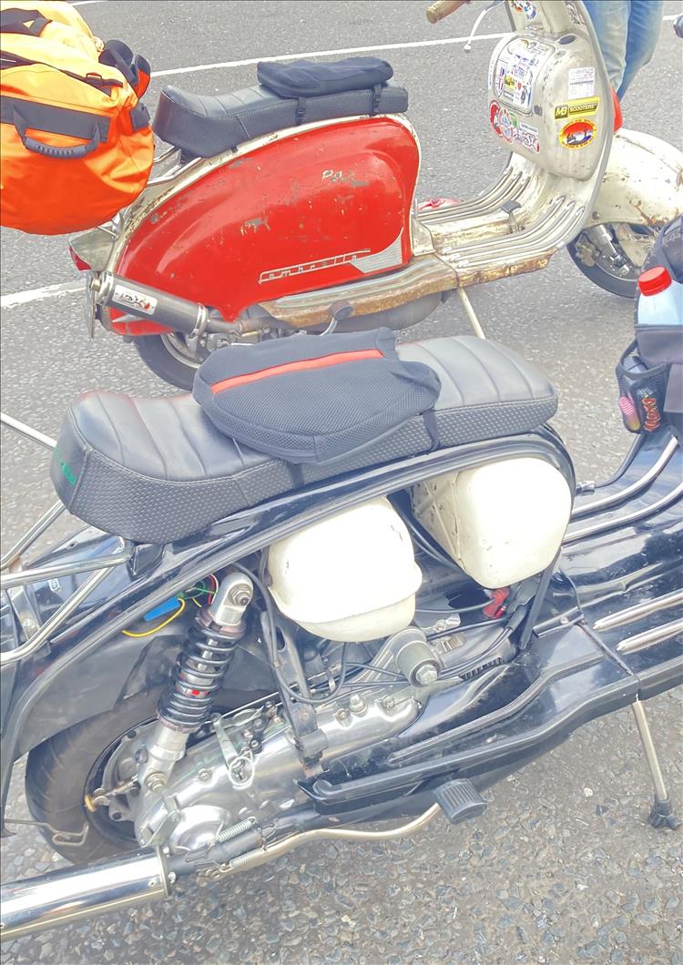 One scooter has panel removed showing the engine, another we see with the camping gear
