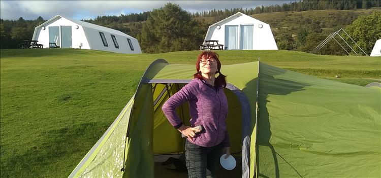 Sharon smiles and looks proud and smug by the tent at the campsite on Mull