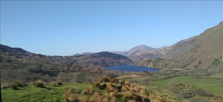 Steep hillsides, a Llyn, grasses and trees with clear blue skies near Beddgelert