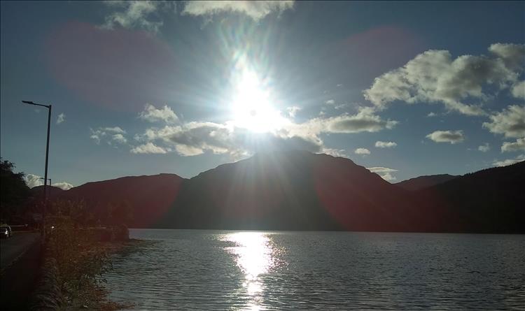 The sun is setting behind a Highland mountain seen from the town or Arrochar