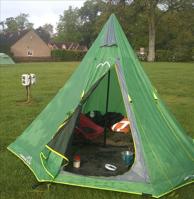 A tall green teepee tent filled with Ren's camping kit