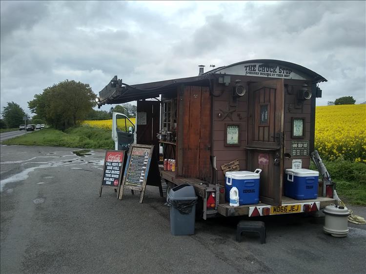 A food van that looks like an old west wooden shed beside a field of yellow rape seed