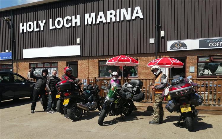 5 riders and their bikes in the sunshine outside the Holy Loch Marina Cafe