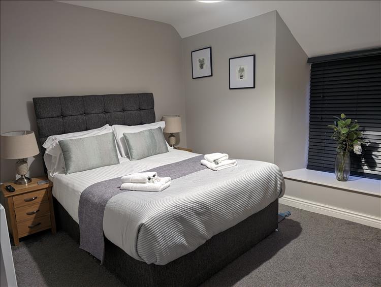 A smart crisp bedroom with bed, looking rather posh
