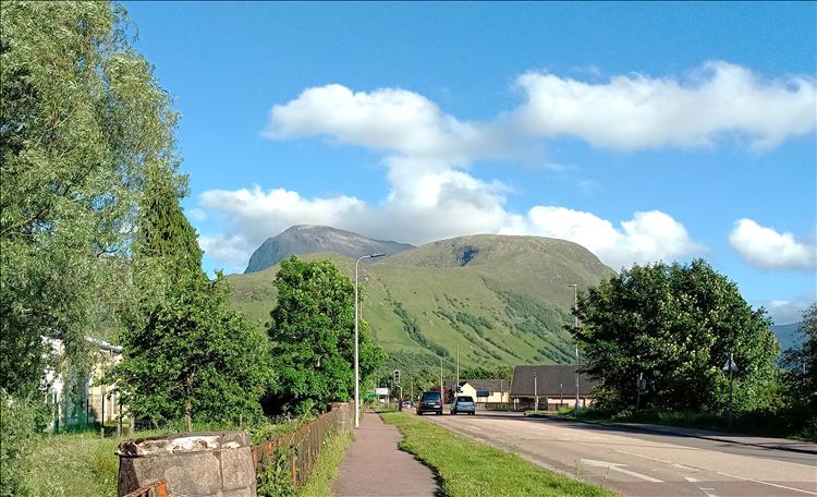 Between trees and the road we see the peak of Ben Nevis with no visible snow