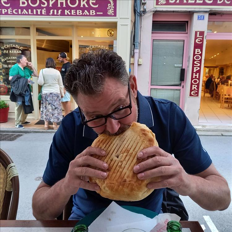 A man eating a large round huge kebab in Cluny France