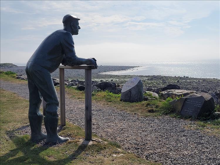 A life size bronze statue of a fisherman looking out to sea at Port William