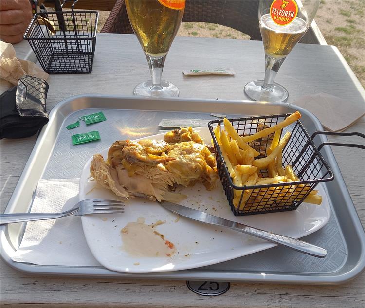 Half a chicken and a small basket of chips, and a couple of French beers on a table