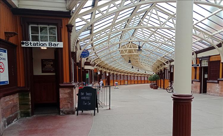 The white painted victorian steel roof frame curves away into the distance at the train station