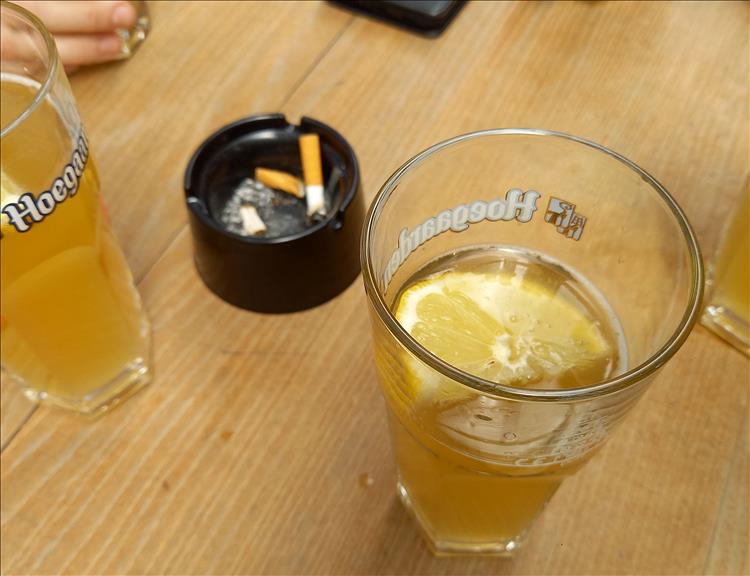 A beer on a table with a lemon in it in the town centre