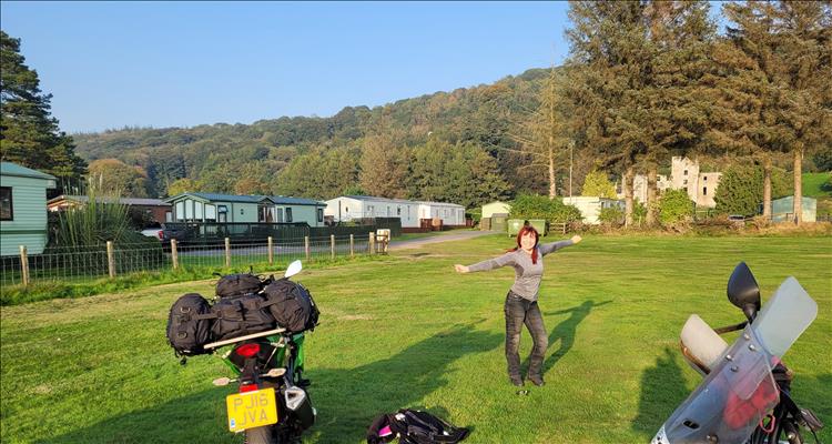 Sharon happy in the sunshine at the campsite. Trees and hills and static caravans