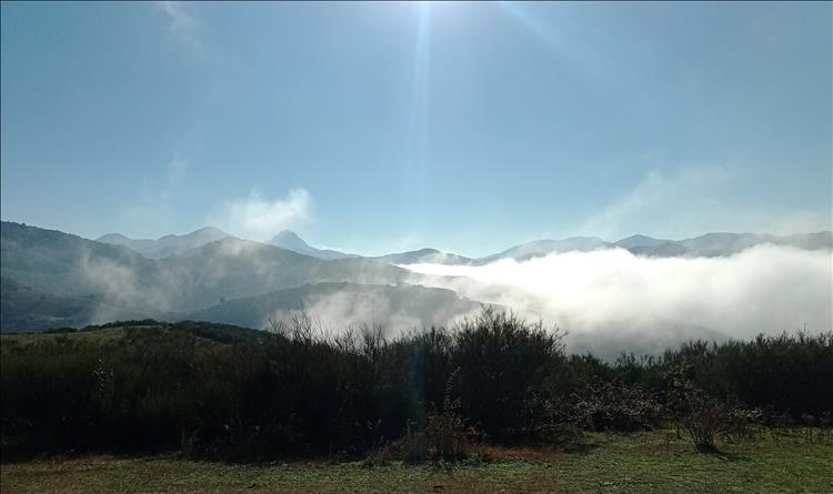 Mountain tops stretching out into the distance with hazy mist and blue skies