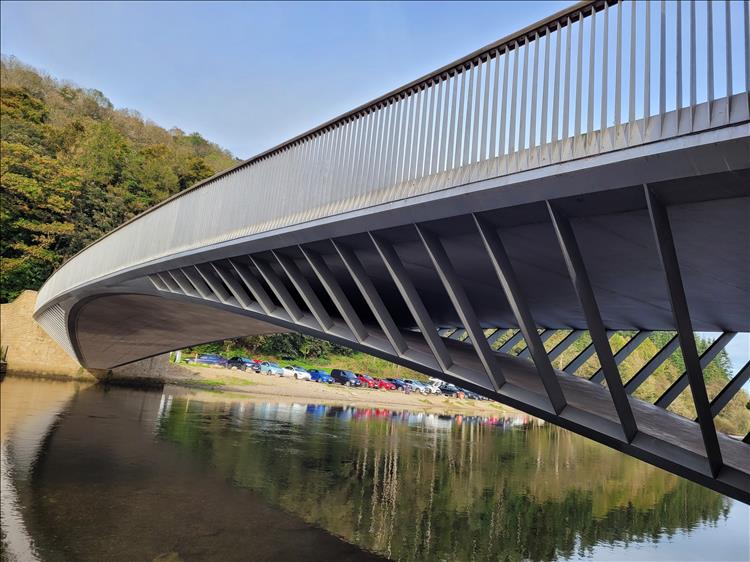 A curved steel structure across the cam river at Pooley Bridge