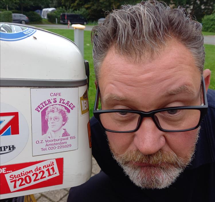 A chap looks mournful by his motorcycle top box for reasons unknown