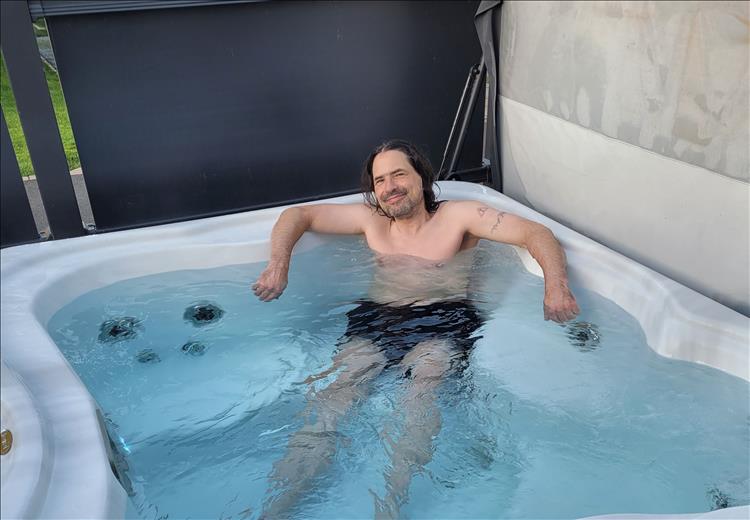 Ren lounges in the hot tub giving a wry smile