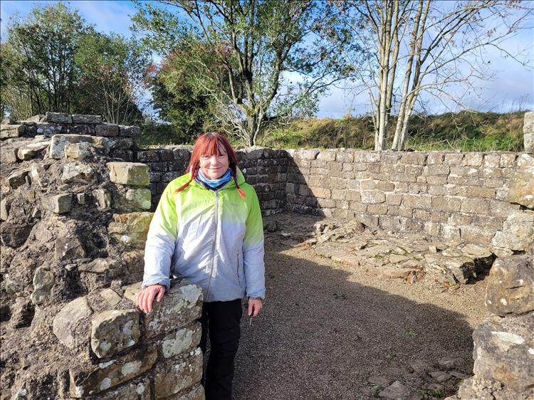 Sharon smiling in the sun at Hadrian's Wall, just a low stone wall these days
