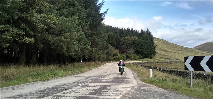 Rolling hills, trees, a winding road and Sharon on her Kawasaki
