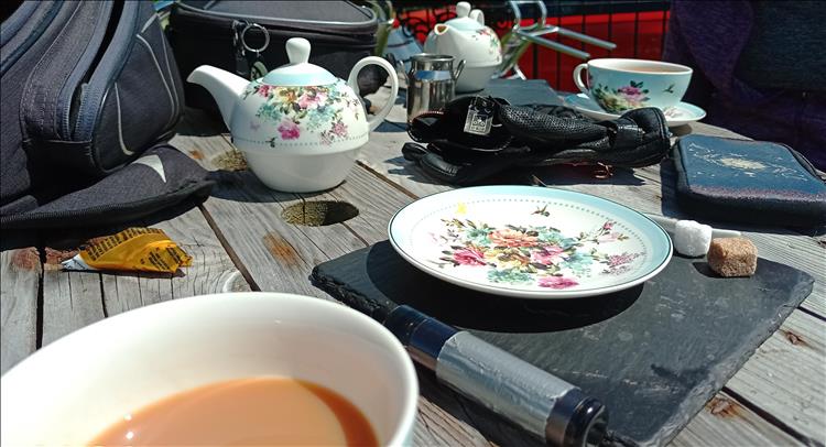 On the table we see tea and teapots, motorcycle bags in bright sunshine