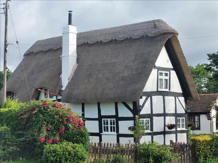 An old timber framed and heavily thatched house in the village
