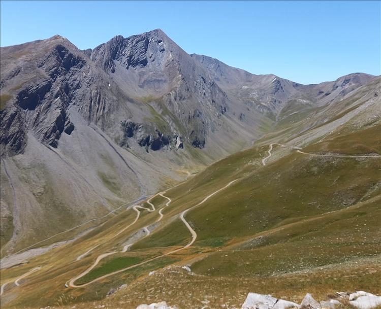 A very twisting and dusty dirt track wriggles and wendles it's way up a valley in the Alps