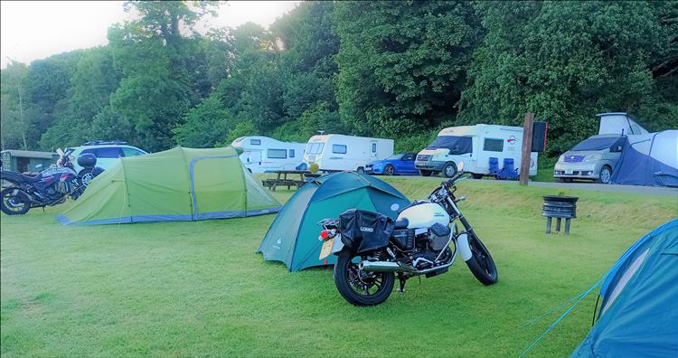 A Guzzi V7 next to the tents and campervans at Silvercraig's Campsite