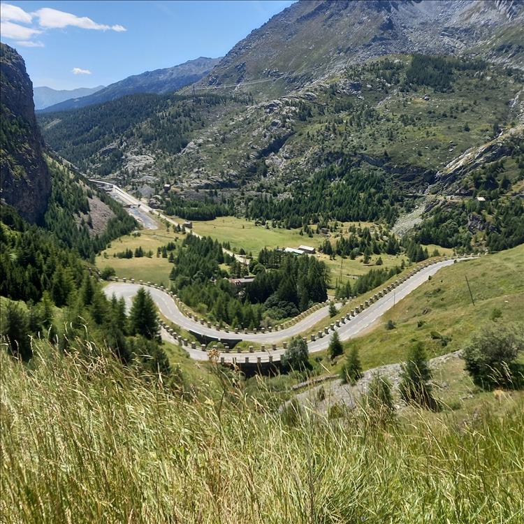 Looking down into a vast valley there's a very twisty and bendy road climbing the side of the mountain