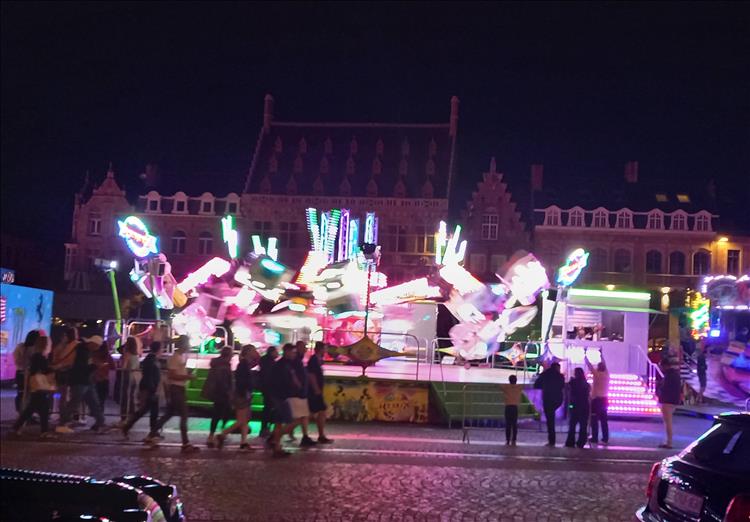 A blurry nighttime image of the bright lights on a ride in the streets of Ypres