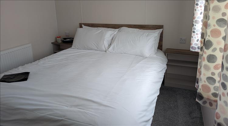 A regular double bed in a static with clean sheets and a radiator