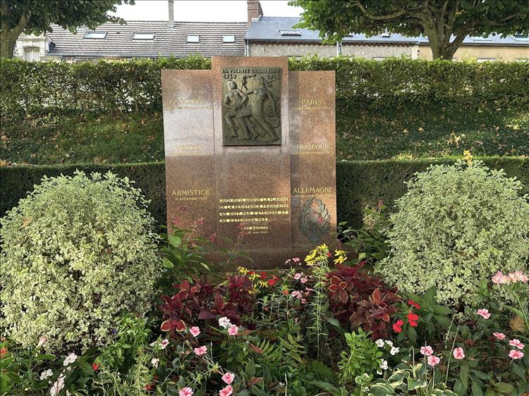 A large polished stone in a pretty garden with a memorial to WW2