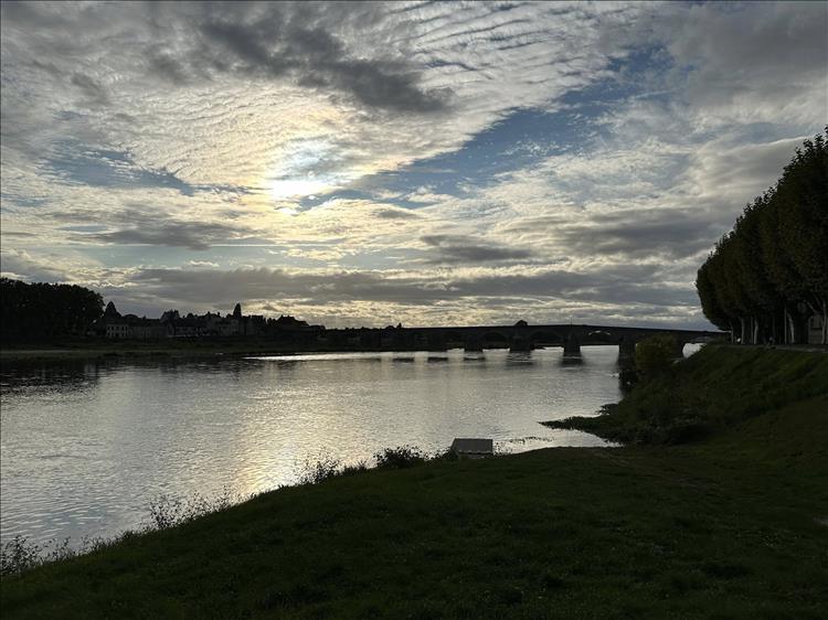 A dark outline of a bridge at Gien against a dramatic evening sky